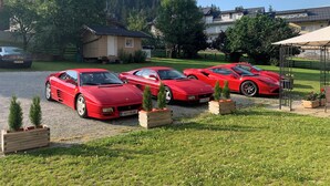 A driveway with five red sports cars parked in a row. - Apartment Hotel Panorama (Wagrain)