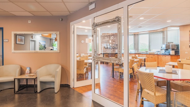 Un espace repas moderne avec des chaises blanches, une cloison en verre et un panneau indiquant l’emplacement du buffet.