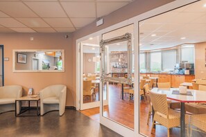 Een moderne eetruimte met witte stoelen, een glazen scheidingswand en een buffetbord.