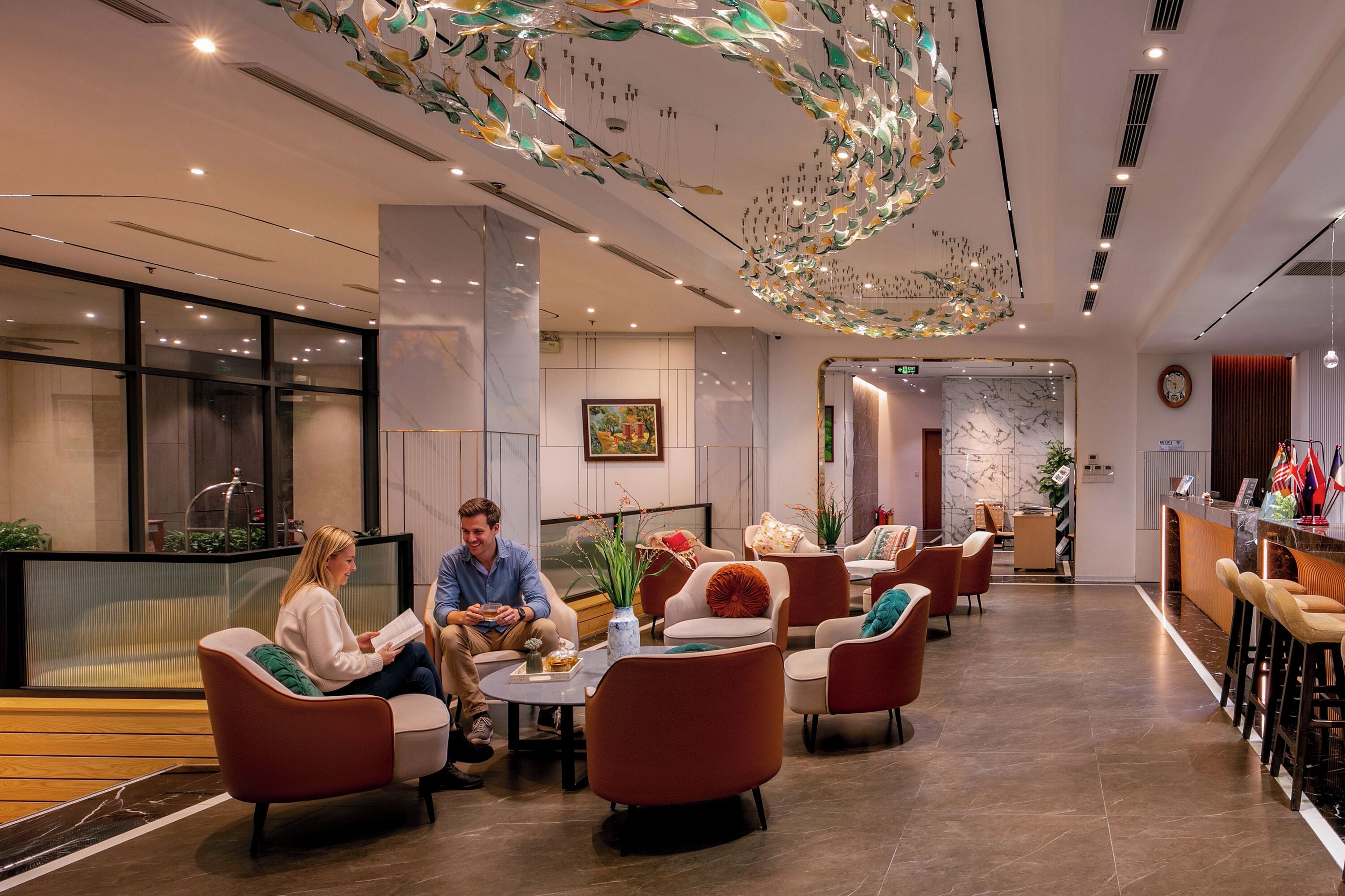 A modern lobby with a reception desk, seating area, and a decorative ceiling.