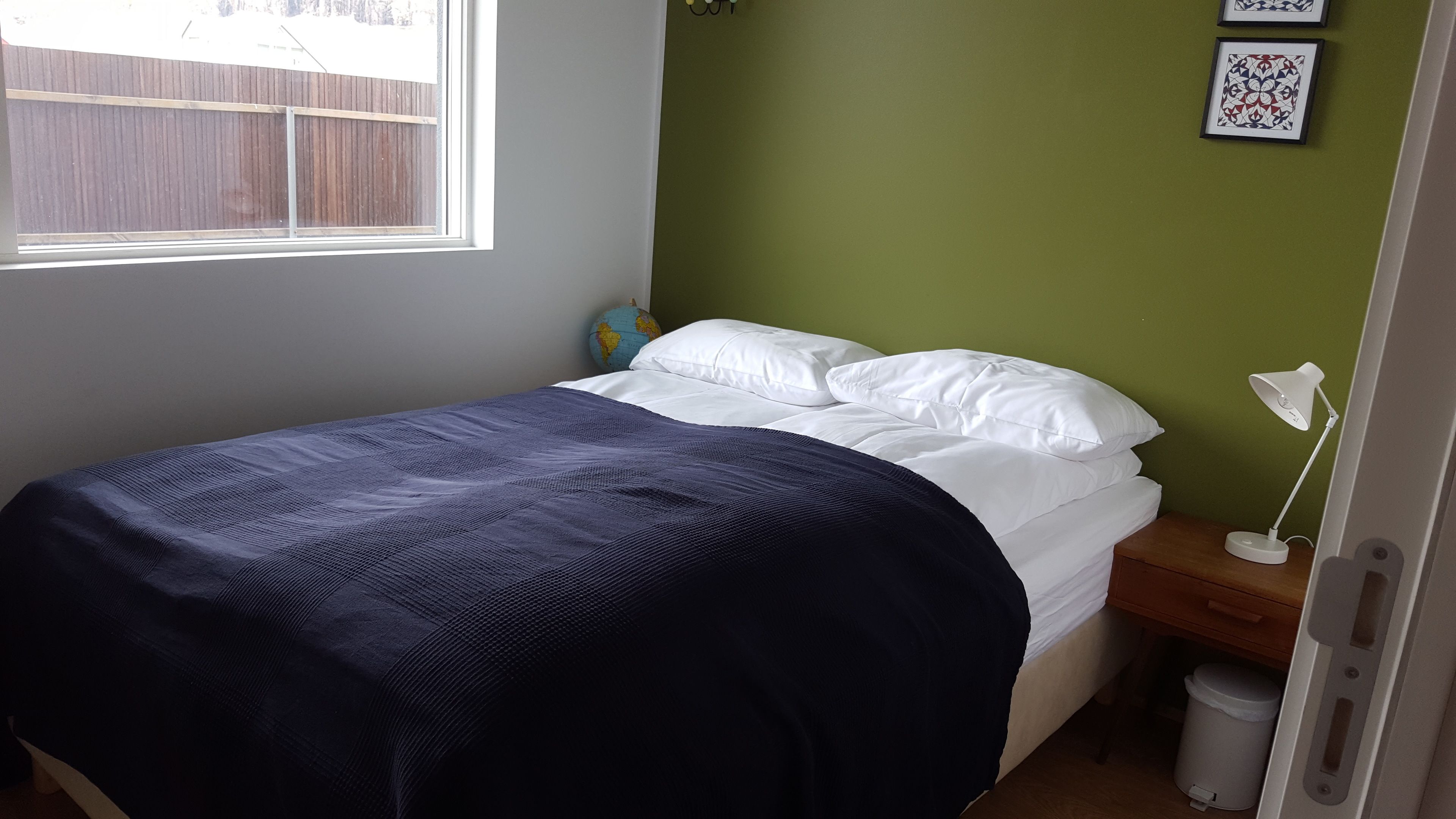 Un dormitorio con una cama, una mesita de noche, un globo terráqueo y una lámpara de pared.