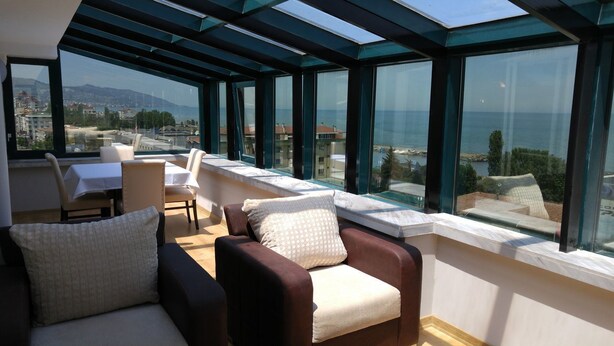 A sunlit room with a view of the sea, featuring a sofa, chairs, and a table. - Konak Park Hotel (Akçaabat)