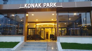 The entrance to Konak Park with a glass facade, outdoor seating area, and a staircase leading up to the entrance. - Konak Park Hotel (Akçaabat)