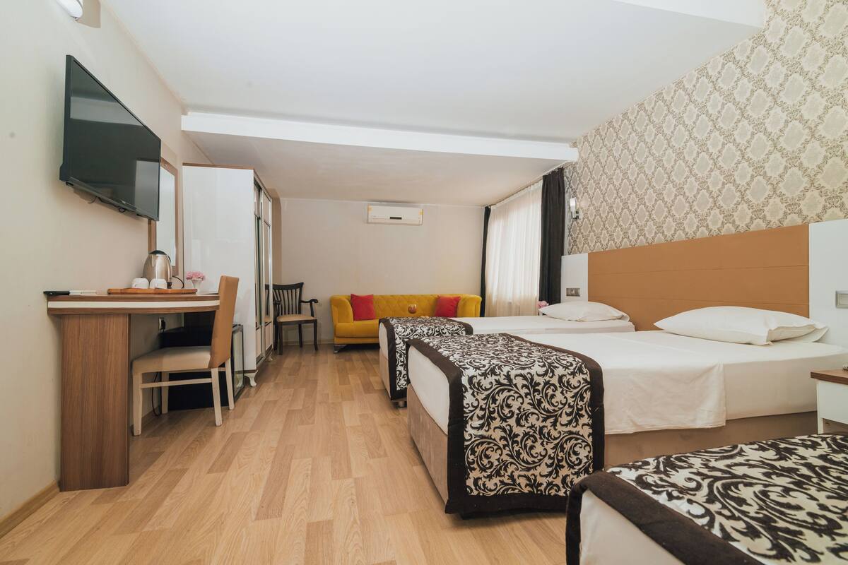 A hotel room with two beds, a desk, a television, and a sofa.
