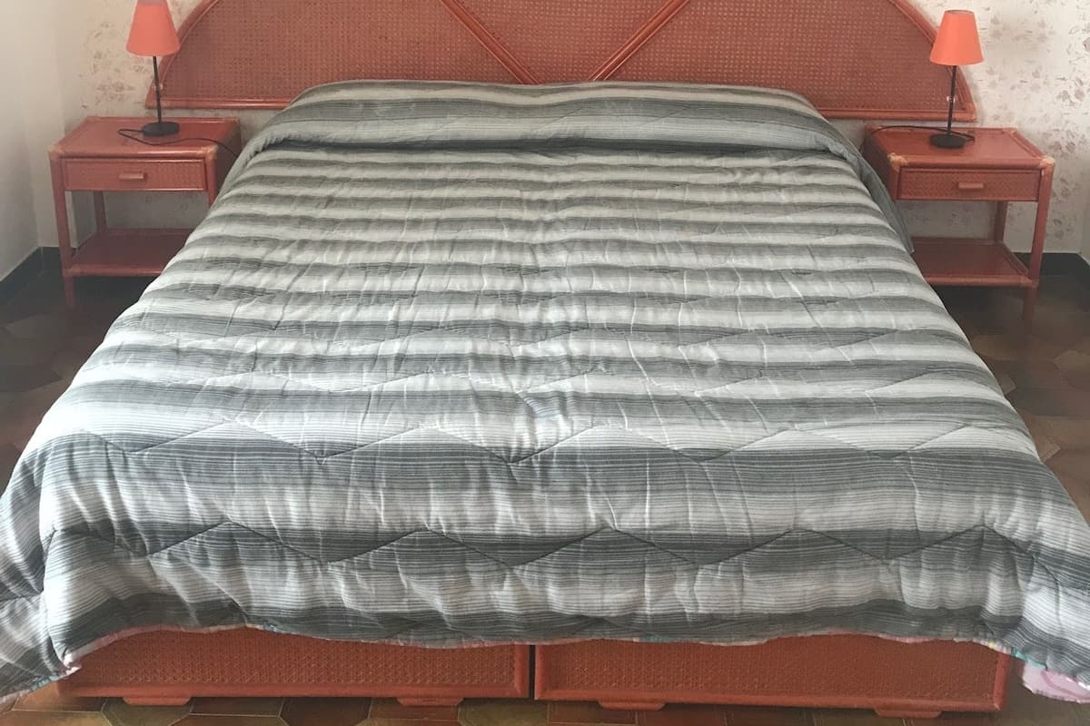 A bed with a striped bedspread, two nightstands with lamps, and a patterned wall.