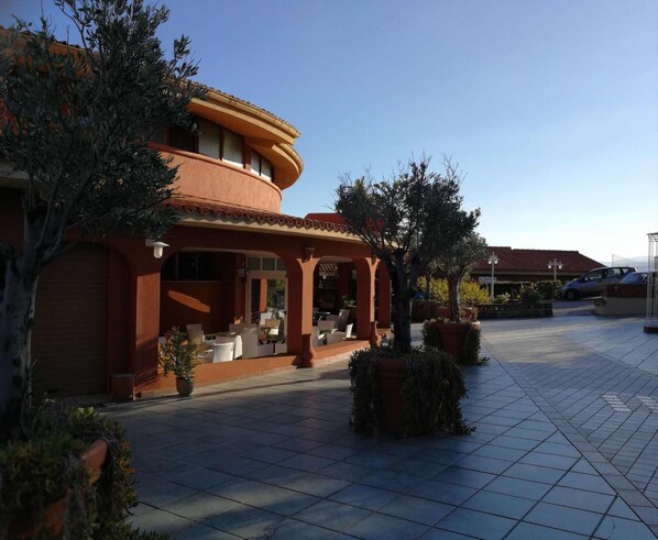 A building with a patio area, outdoor seating, and potted plants.
