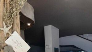 A wooden sculpture with a starfish and a note, a round wooden table, and a view of a spacious room with a large window and a potted plant. - Baia dell'est (Montauro)