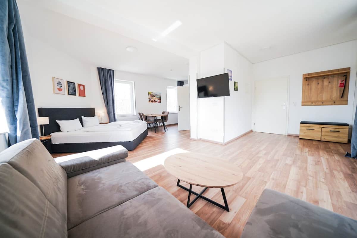 Una habitación de hotel moderna con una cama grande, un sofá, una mesa de comedor y un televisor.