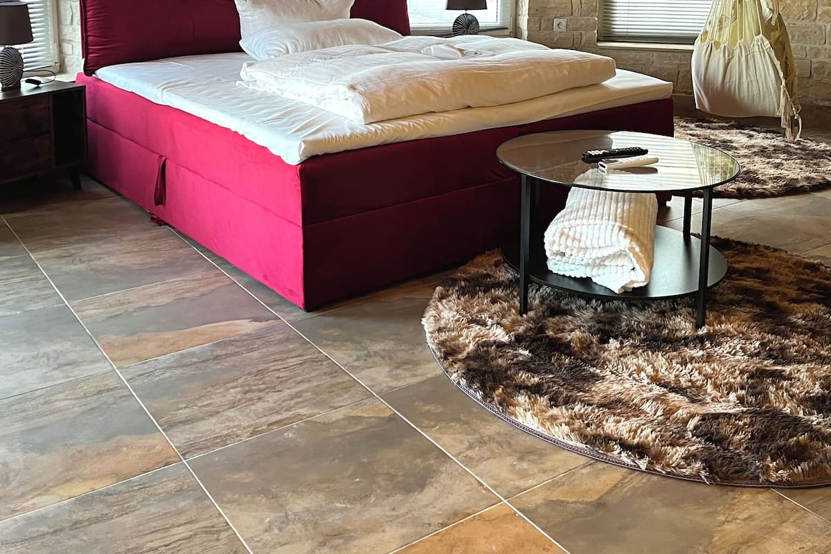 Un dormitorio con cama roja, paredes de piedra y techo de madera.