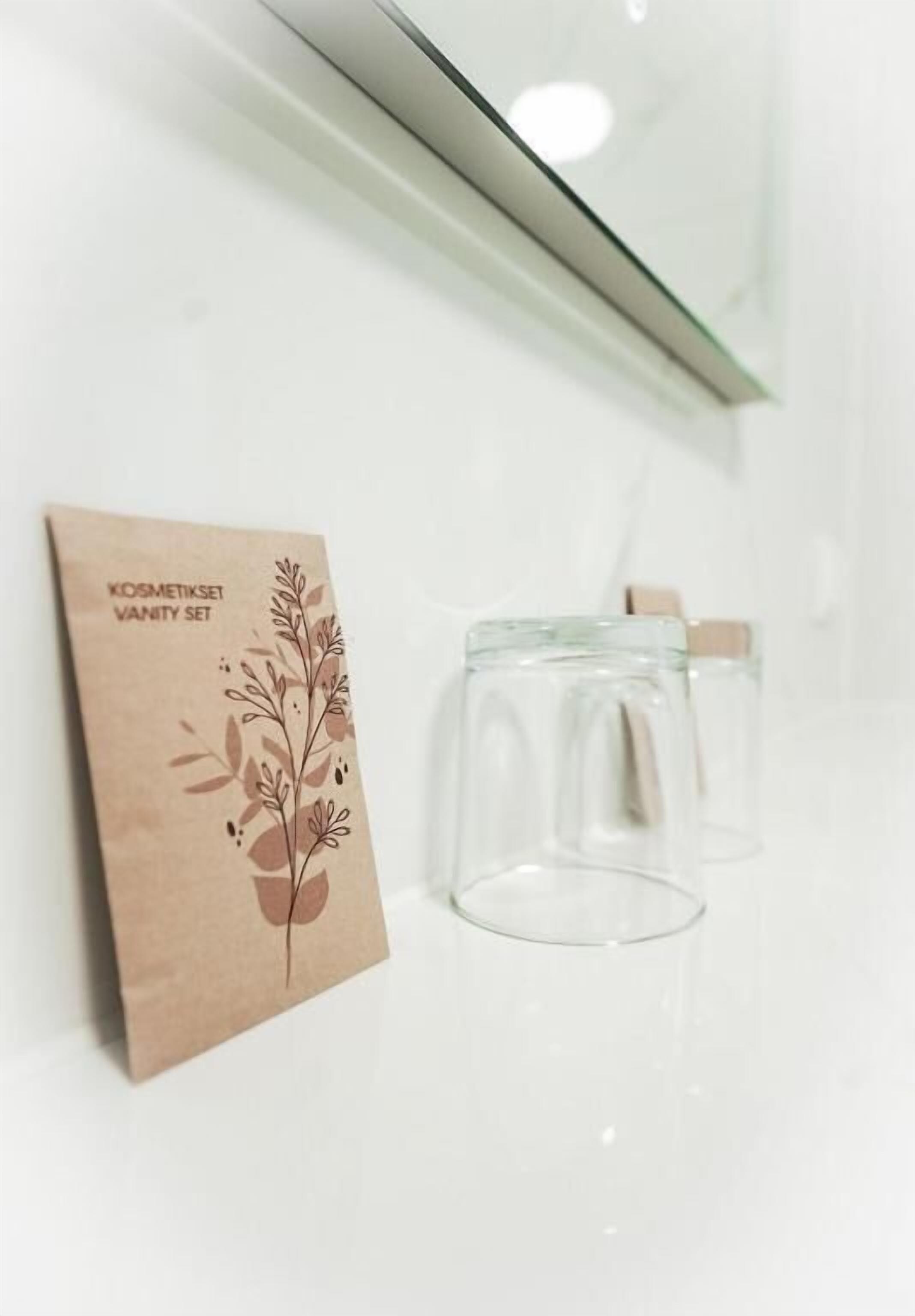 A wall-mounted paper bag with a floral design and text, and two clear glasses.