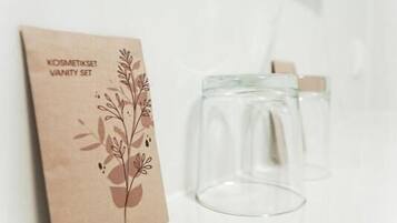 A wall-mounted paper bag with a floral design and text, and two clear glasses.