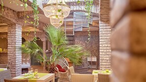 Un comedor interior acogedor con mobiliario de mimbre, plantas colgantes y una araña.