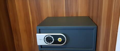 Una caja fuerte Yale con un dial de combinación y un botón de bloqueo, sobre un fondo de madera.