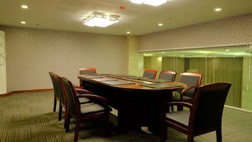 A conference room with a large oval table, six chairs, and a glass partition.