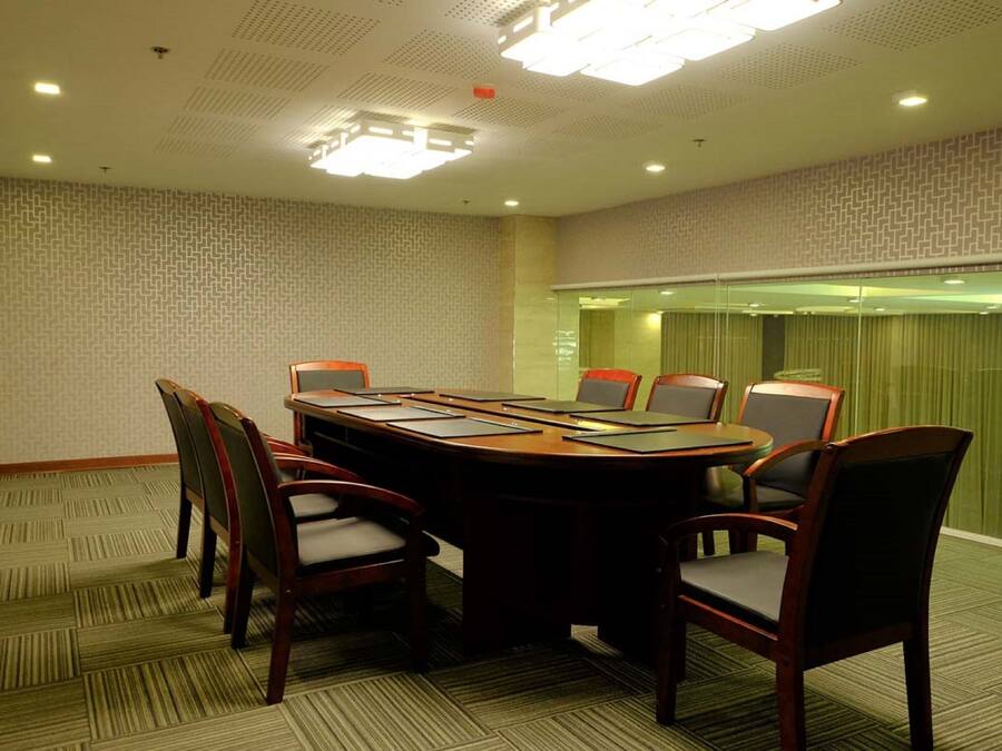 A conference room with a large oval table, six chairs, and a glass partition.