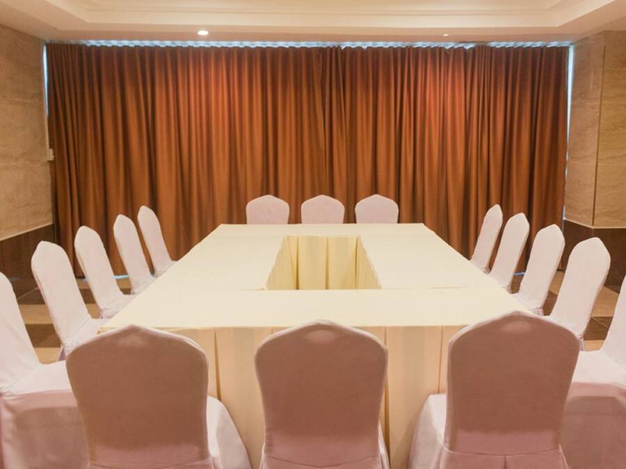 A conference room with a long table and chairs, a curtain backdrop, and a tiled floor.