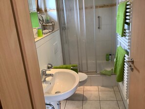 Un baño con lavamanos, inodoro y ducha.
