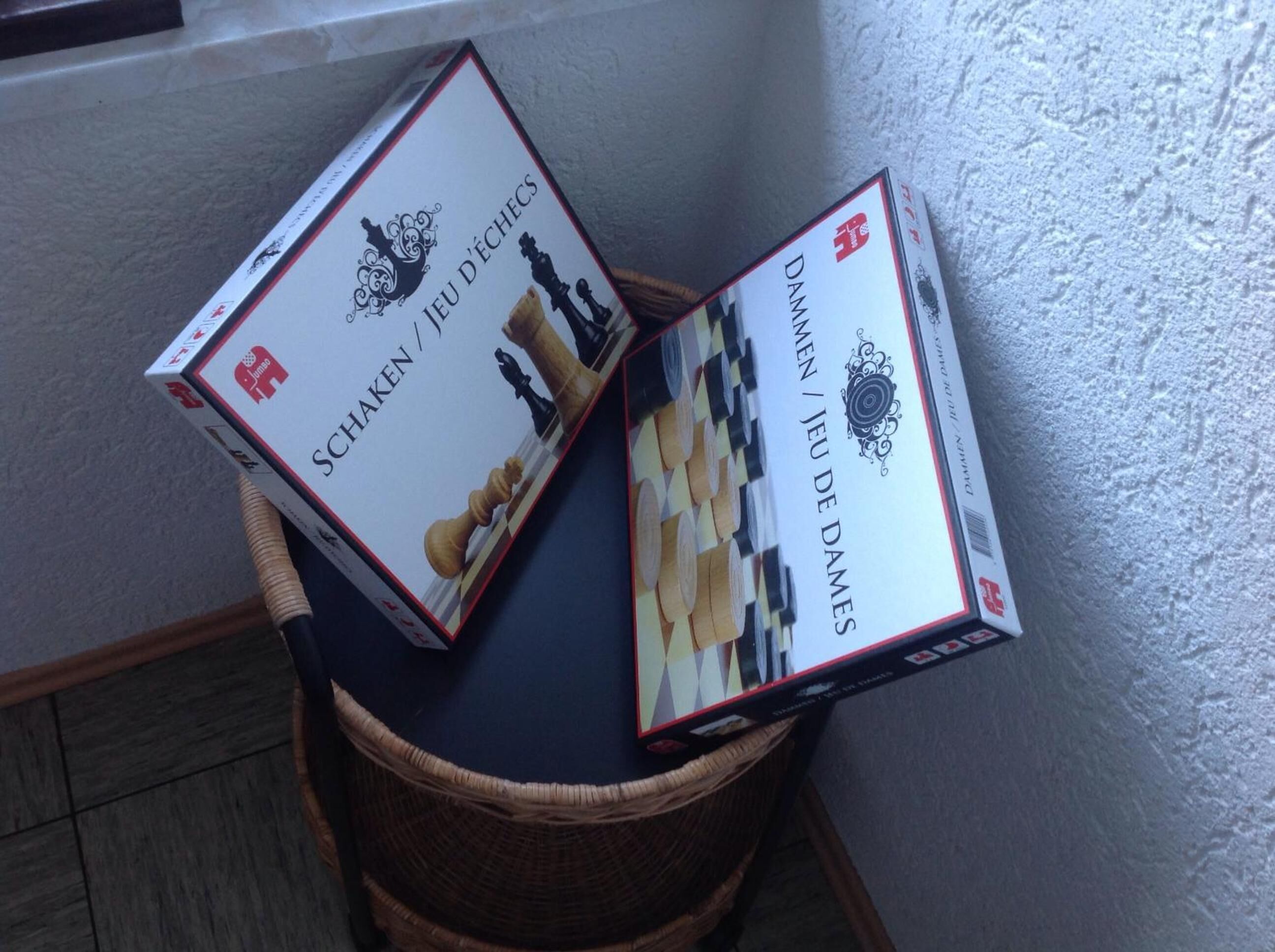 Two chess sets in wicker baskets against a textured wall.