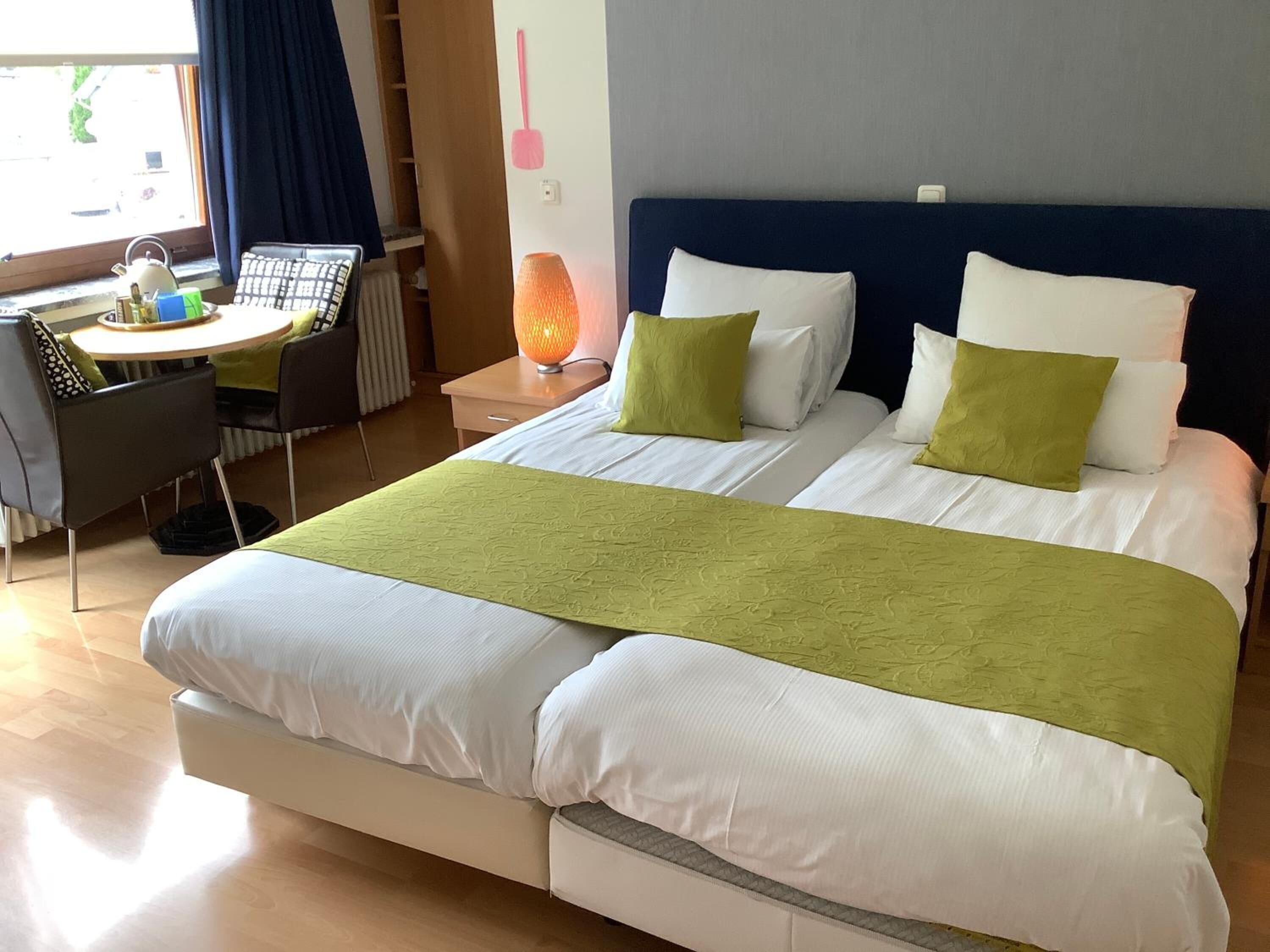 A hotel room with two beds, a desk, and a chair.