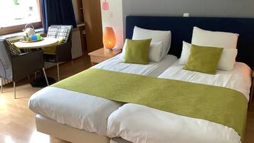 A hotel room with two beds, a desk, and a chair.