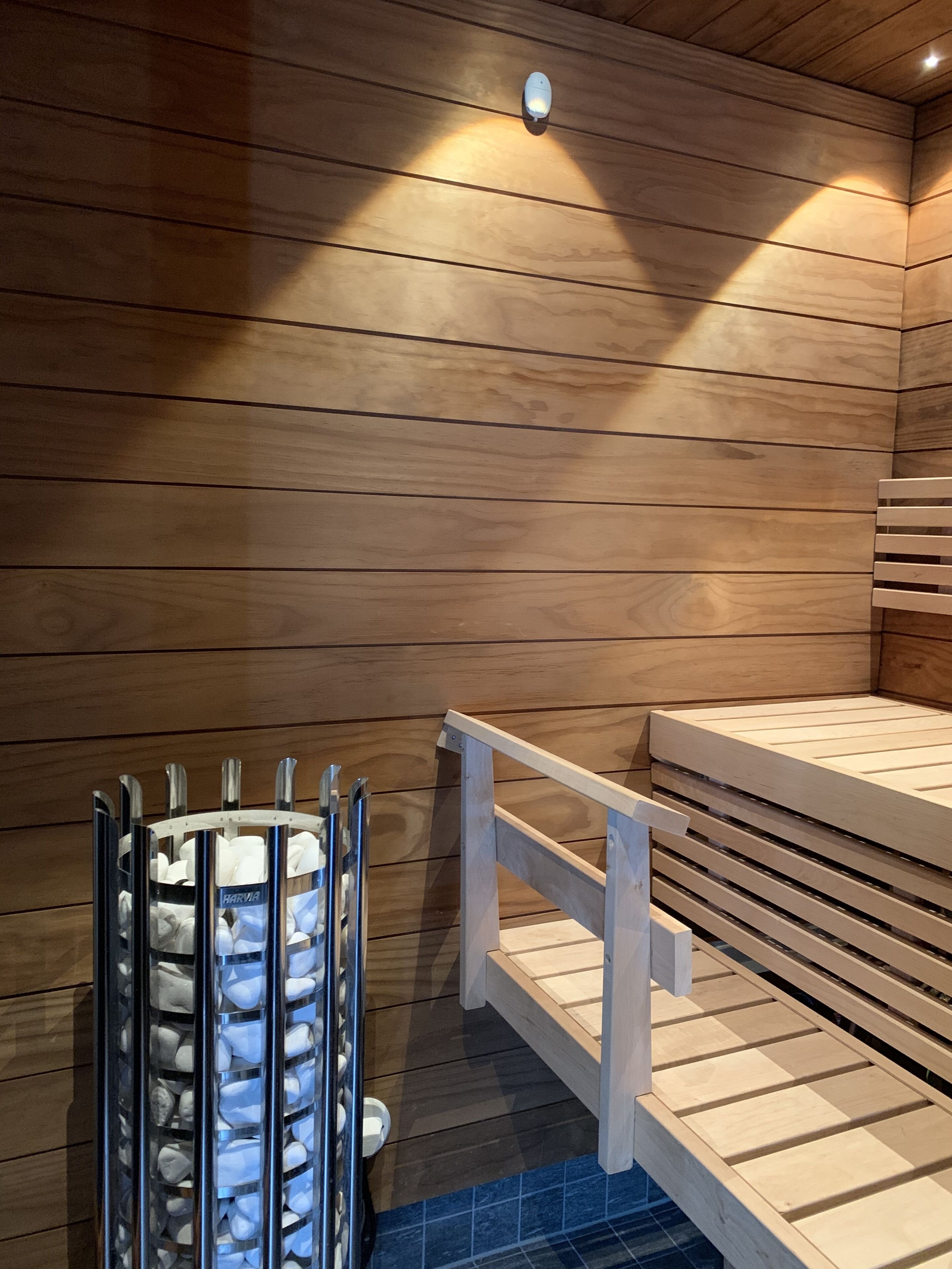 A wooden sauna with a bench and a metal sauna heater.