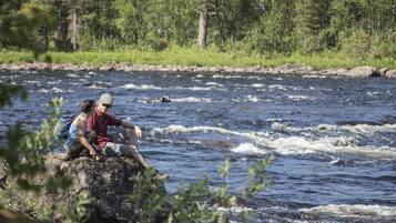 Two people sitting on a rock by a river.