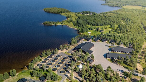 An aerial view of a lakeside property with multiple cabins, a central building, and a parking area.