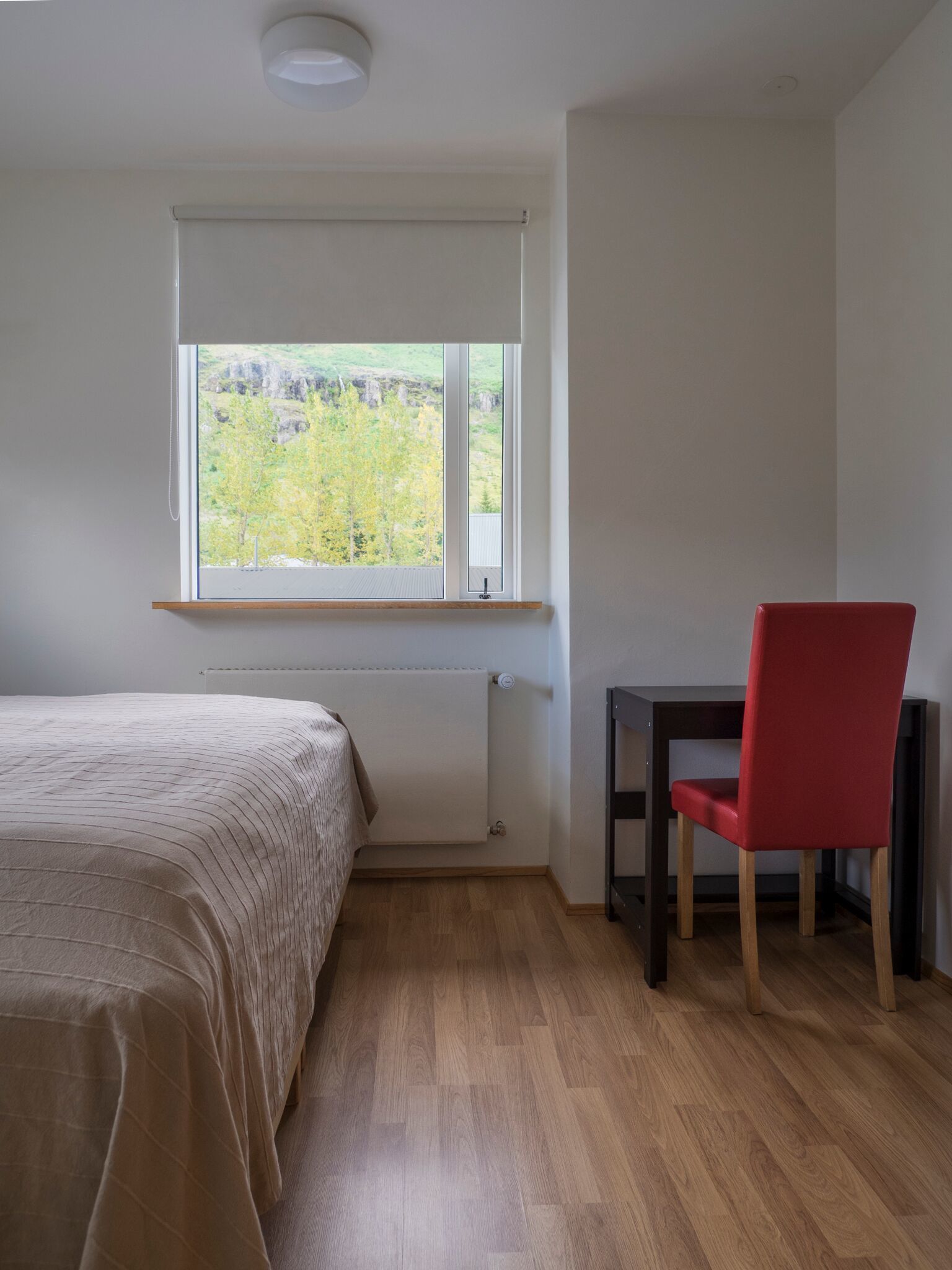 A bedroom with a bed, a desk, and a chair.