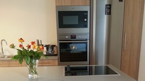A modern kitchen with a central island, stainless steel appliances, and wooden cabinetry. - Seyðisfjörður Guesthouse (Seydisfjordur)