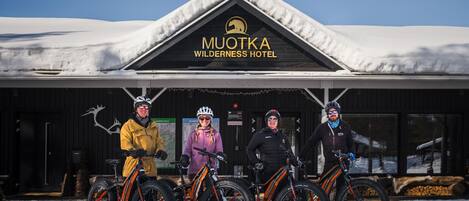 Exterior do Hotel Muotka Wilderness com telhado coberto de neve e uma placa com o nome do hotel.