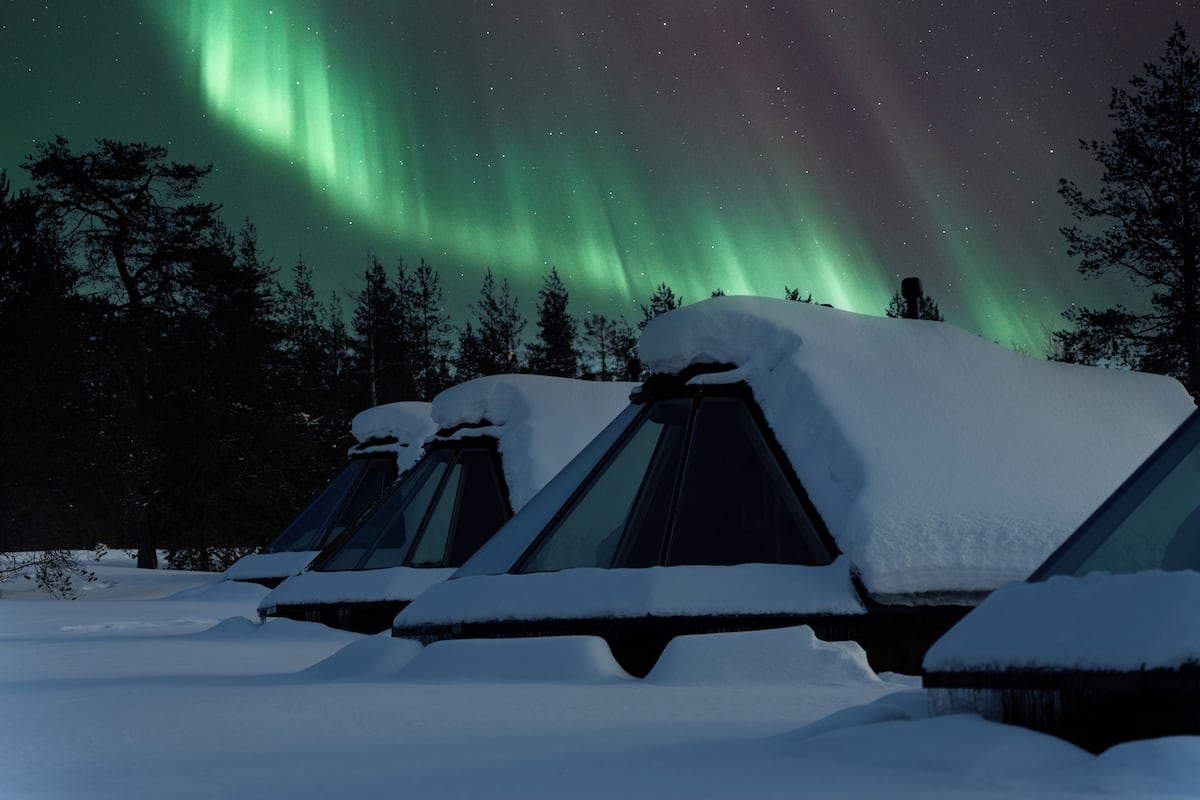 Une rangée de tentes recouvertes de neige, offrant une vue sur les aurores boréales.