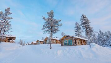 Ein Ferienresort mit Blockhütten, umgeben von schneebedeckten Bäumen und einem klaren Himmel.