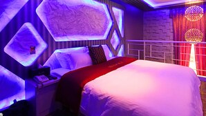 Una habitación de hotel moderna con una cama grande, una mesita de noche y una lámpara fijada a la pared.