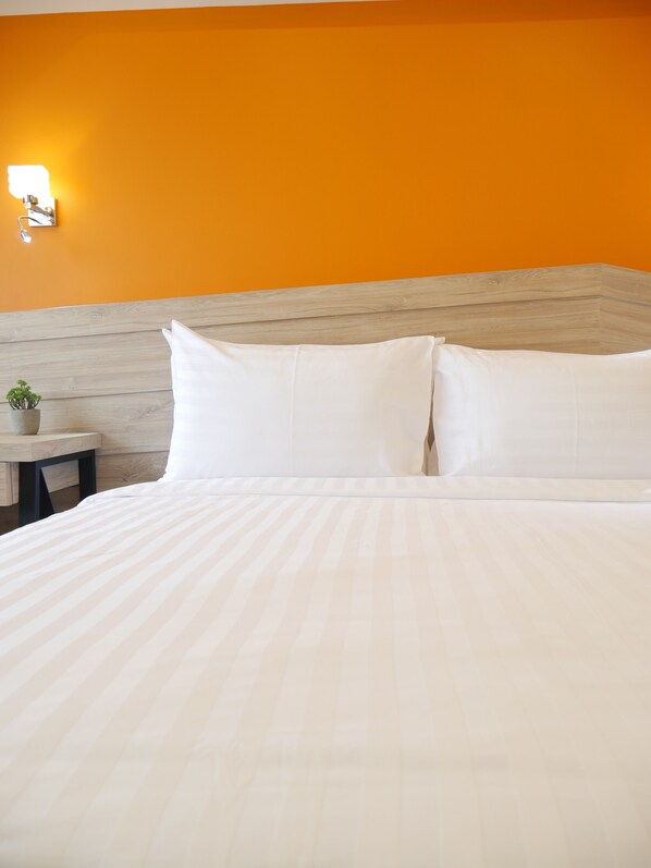 A hotel room with a bed, a nightstand, and a wall-mounted lamp.