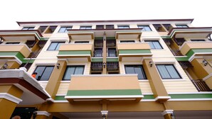 Ein mehrstöckiges Gebäude mit einer symmetrischen Fassade, das Balkone und Fenster aufweist.