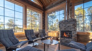 A cozy room with large windows, a stone fireplace, and comfortable seating. - Wilderness Hotel Nangu & Igloos (Inari)