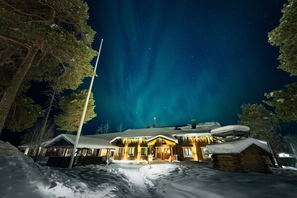 A snow-covered lodge with a wooden exterior and a snow-covered roof, surrounded by trees.