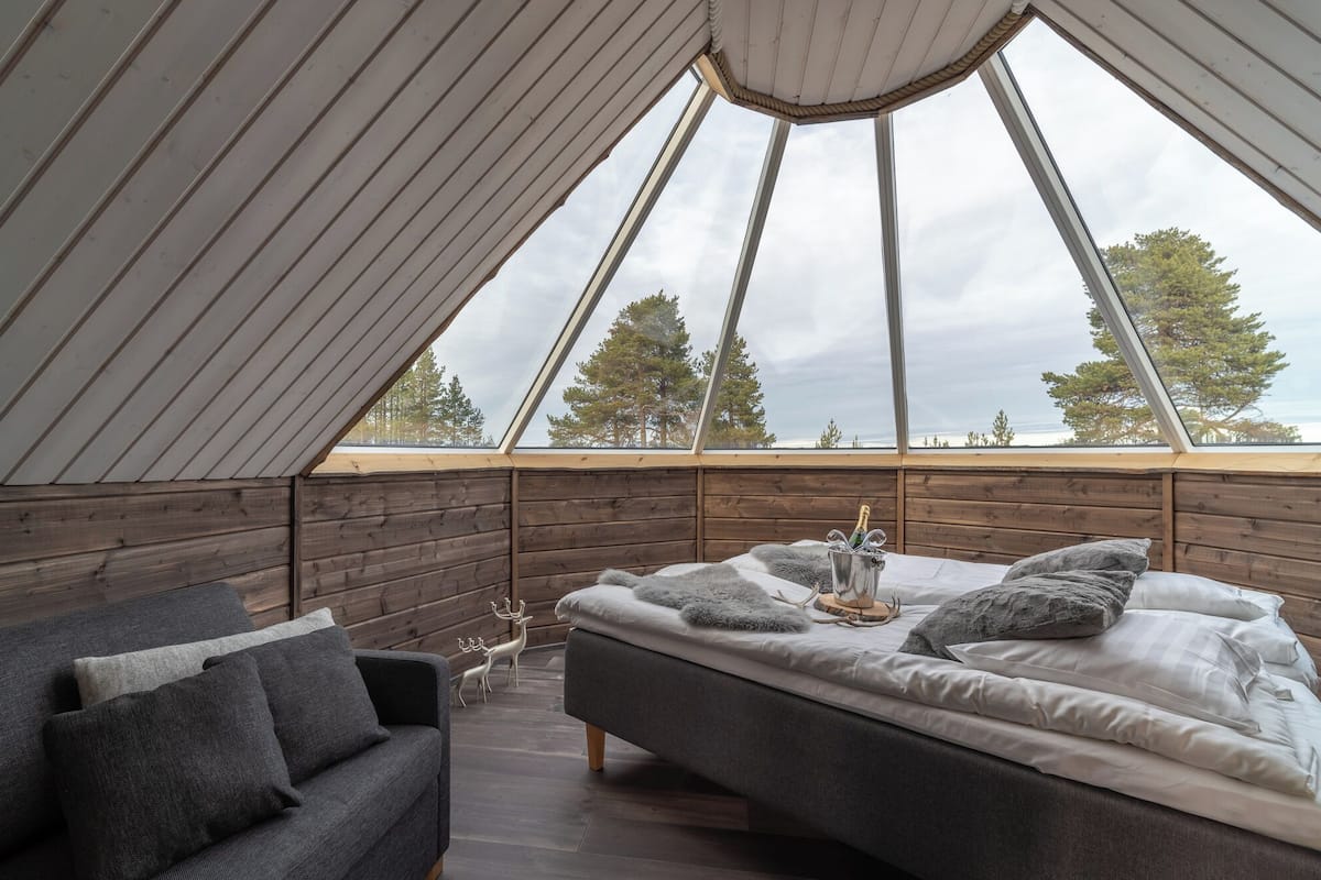 Un cuarto acogedor con techo inclinado, paredes de madera y una cama con almohadas y un objeto decorativo.