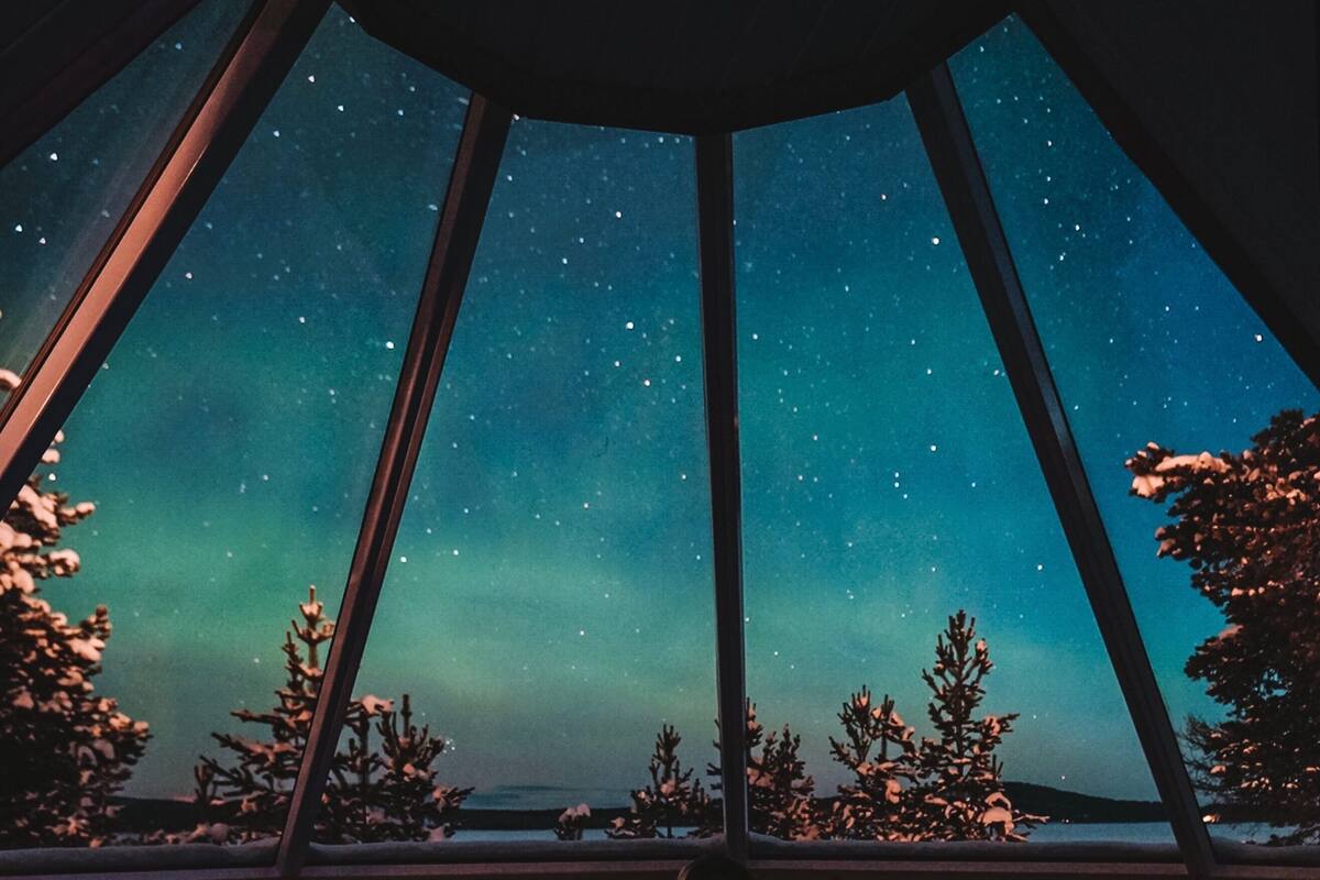 Ein Zimmer mit einem Bett, einem Fenster und Blick auf den Nachthimmel.