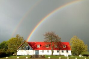 A house with a red roof and white walls, surrounded by trees and a lawn. - Tryde 1303 Bed & Breakfast (Tomelilla)