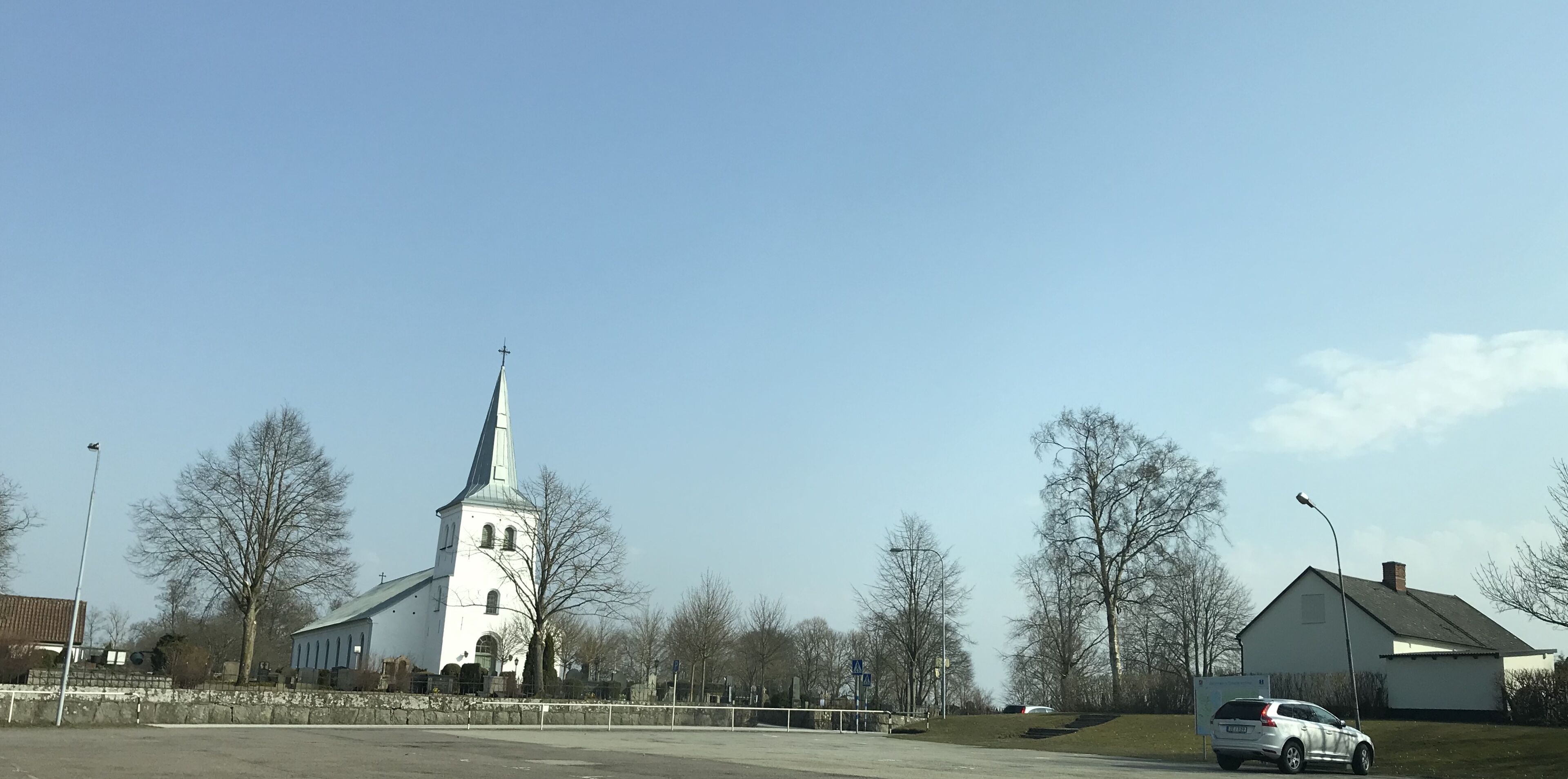 Una iglesia con un campanario alto y un edificio pequeño contiguo.