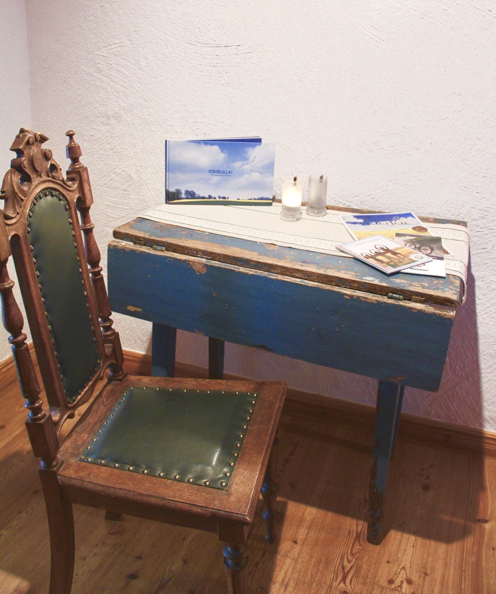 Un escritorio de madera con cubierta azul y una silla con asiento acolchado verde.