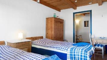 Un dormitorio con dos camas, un armario de madera y un escritorio con silla.