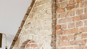 Une pièce avec un mur en briques, un fauteuil de style vintage et un lampadaire.