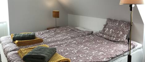 A neatly made bed with a patterned bedspread and multiple folded blankets.