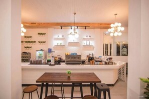 A modern coffee shop interior with a wooden bar counter, stools, and a variety of coffee-making equipment.