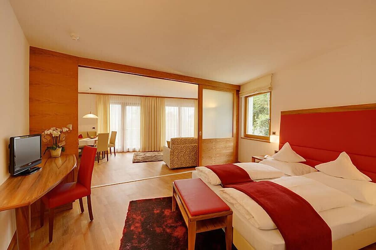 A hotel room with a bed, a desk with a computer, a chair, and a view of the outside through a window.