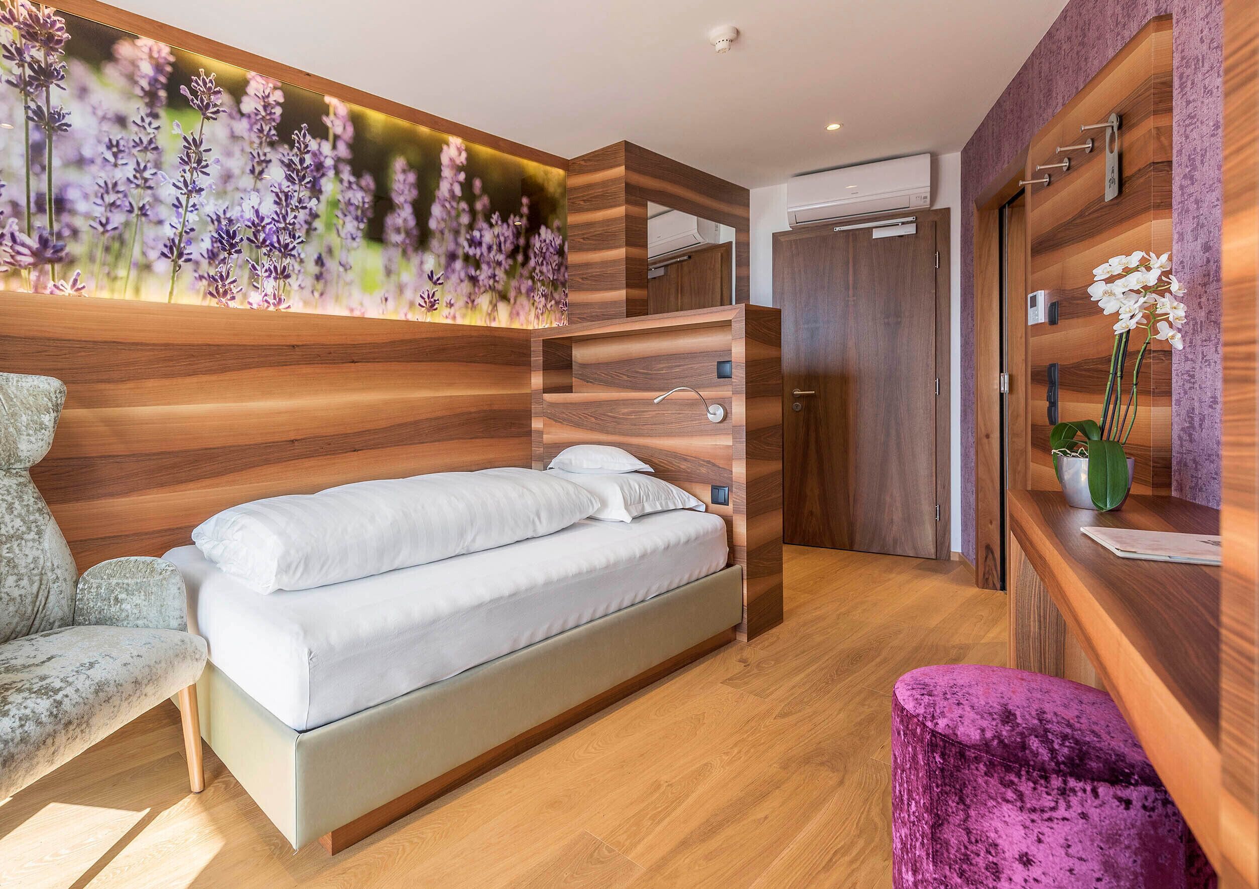 Un dormitorio moderno con cama, tocador con espejo y aire acondicionado de pared.
