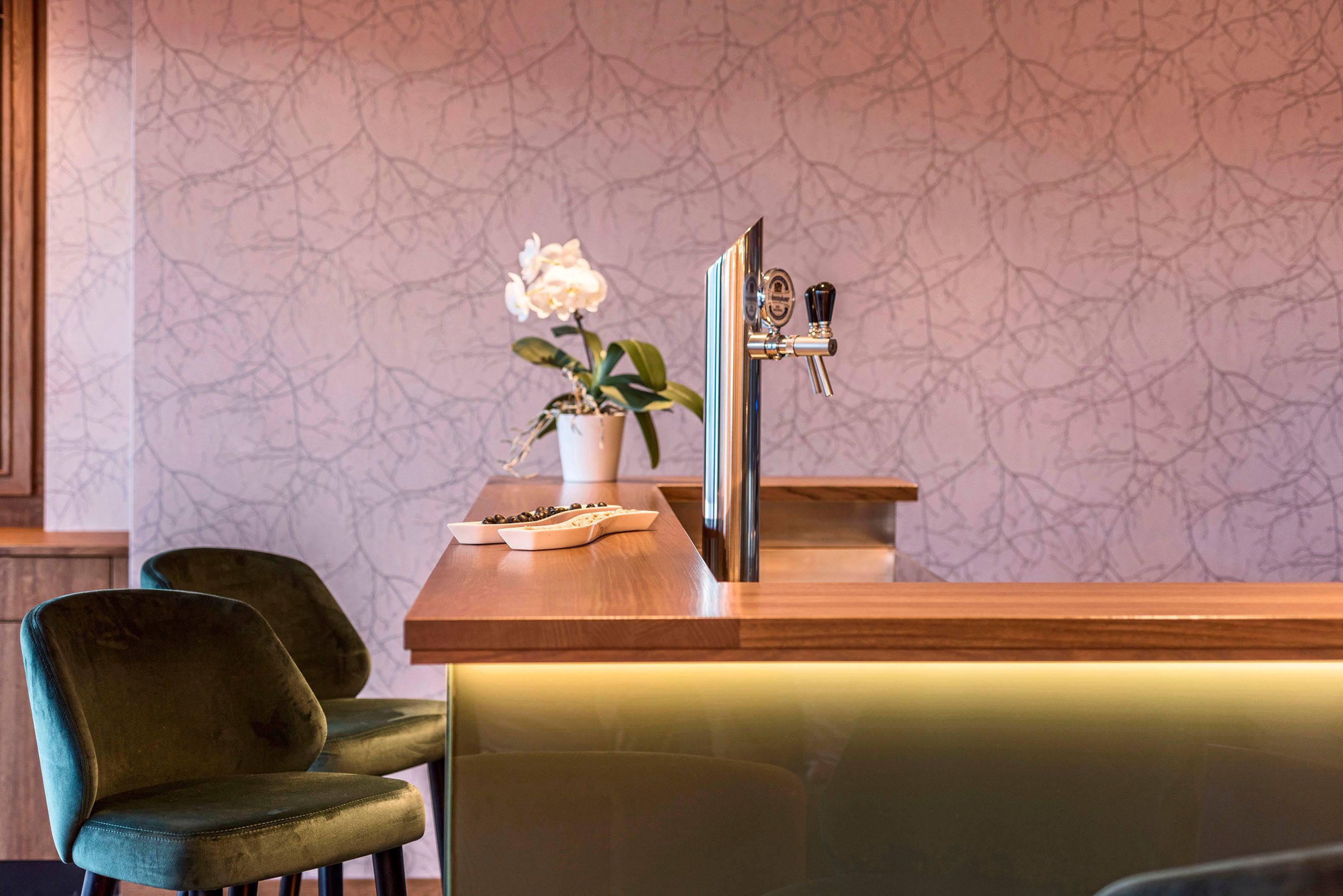 Ein Empfangsbereich mit einem Blumentopf mit Orchidee, einer Holztresen und einer Bar mit Stühlen.