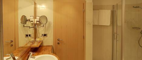 Ein modernes Badezimmer mit einem Holzbettchen, einem großen Spiegel, einem Waschbecken und einer Duschkabine.
